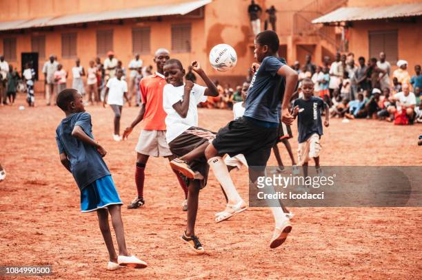 schwarze afrikanische kinder, jungen und erwachsene fußball spielen - poor kids playing soccer stock-fotos und bilder
