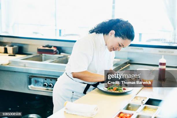 smiling chef plating dish in restaurant kitchen - food plating stock-fotos und bilder