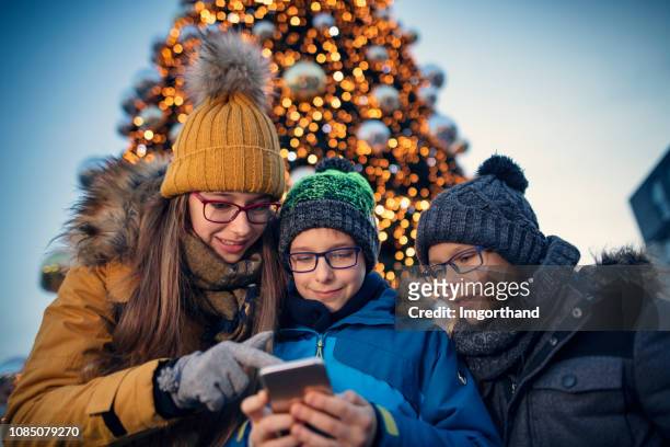 kinder sms am weihnachtsmarkt - teenager boy shopping stock-fotos und bilder