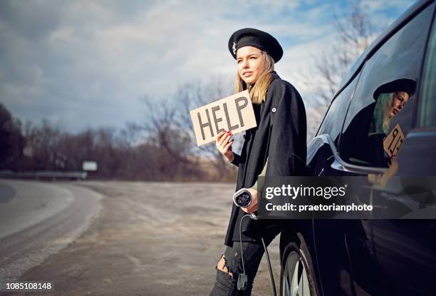 young girl with electric car without power in the battery is looking for help - vehicle breakdown stock pictures, royalty-free photos & images