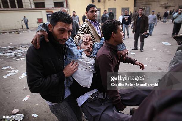 Protestors carry an injured man during clashes with riot police near Tahrir Square on January 29, 2011 in Cairo, Egypt. Tens of thousands of...