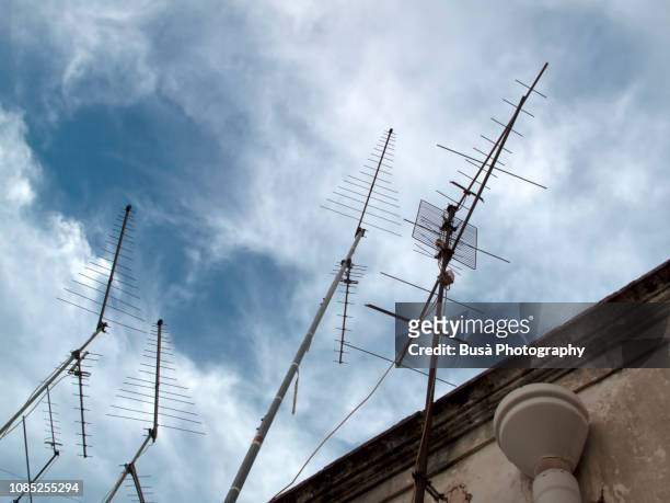 television antennas on roof of old building in italy - fernsehantenne stock-fotos und bilder
