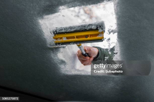 car window being cleared of snow with an ice scraper - weather alert stock pictures, royalty-free photos & images