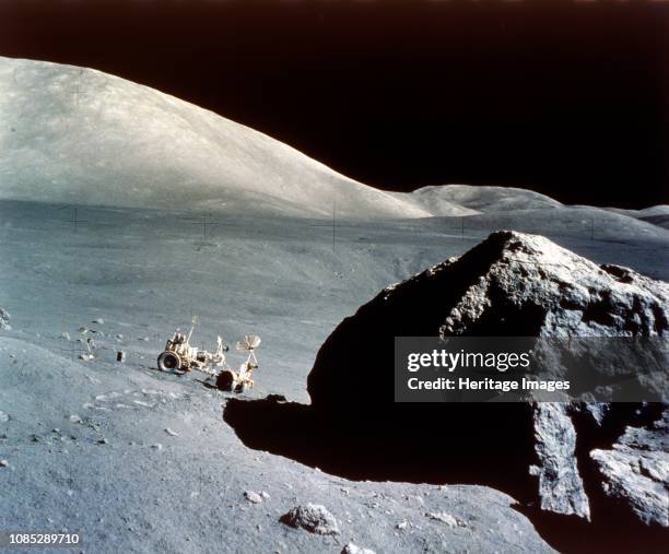 The Rover is dwarfed by a giant rock on the lunar surface, Apollo 17 mission, December 1972. US astronauts Eugene Cernan and Harrison Schmitt...