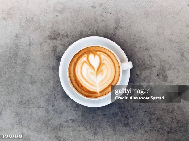 directly above view of cappuccino cup with latte art on concrete table - coffee above stock-fotos und bilder