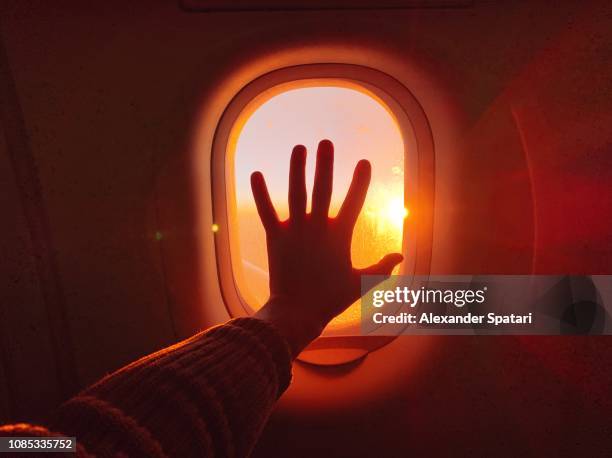 touching plane window while flying in the sky during sunset - flugzeug sonne stock-fotos und bilder