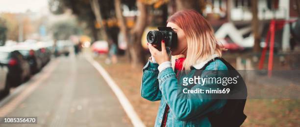 woman with camera taking picture in the street - photography themes stock pictures, royalty-free photos & images