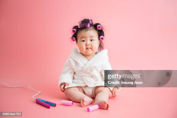 baby sitting on floor, wearing bathrobes. - korean baby girl stock-fotos und bilder