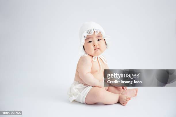 baby sitting on floor, wearing just a diaper. - korean baby girl stock-fotos und bilder