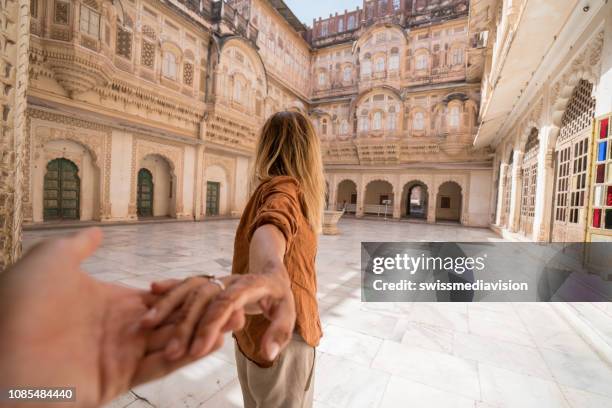 sígueme al concepto; mujer llevando las manos de explotación novio dentro de la fortaleza al atardecer en la india - tirar de fotografías e imágenes de stock