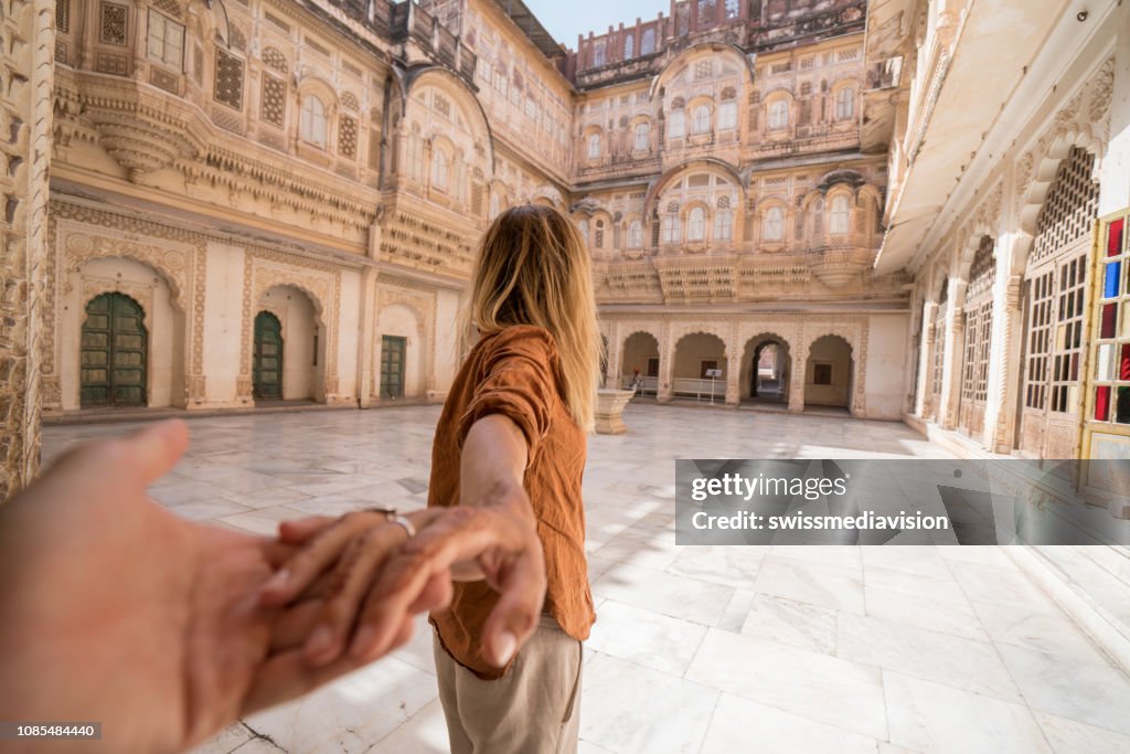 Follow me to concept; woman leading boyfriend holding hands inside the fort at sunset in India