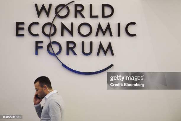 Man using a mobile phone as he walks past a logo at the Congress Center, the venue for the World Economic Forum , in Davos, Switzerland, on Sunday,...
