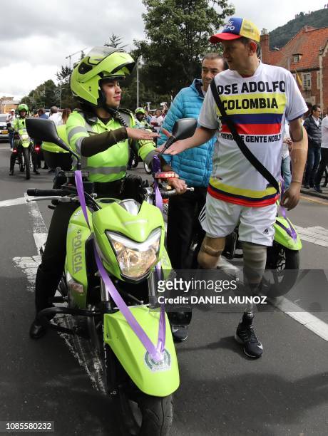 Colombian amputee athlete Jose Adolfo Herrera , greets a Colombian police officer as they take part in a march against terrorism, in repudiation of...