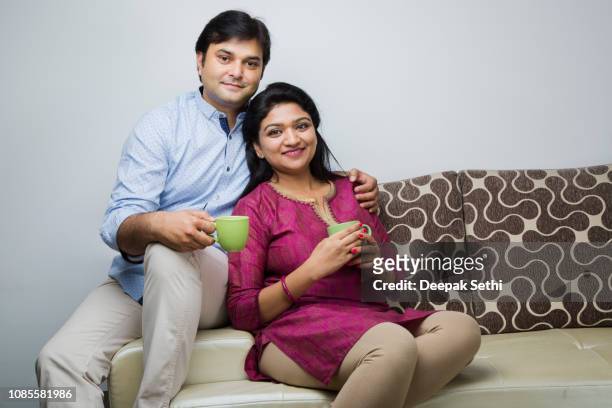 indian couple - stock images - family on couch with mugs stock pictures, royalty-free photos & images