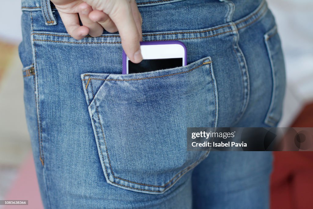 Woman with smart phone in back pocket