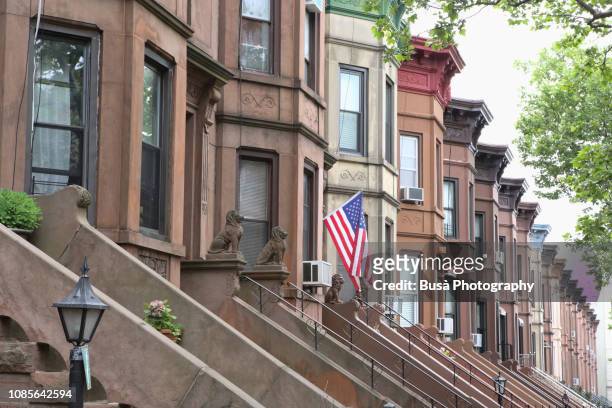 american flag hanging from the front door of a brownstone in a typical middle-class residential neighborhood in brooklyn, new york city. - brooklyn brownstone foto e immagini stock