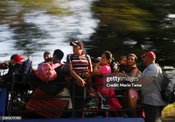 People who are a part of a caravan of Central American migrants ride in the back of a pickup truck, after the driver offered to give them a lift, on...