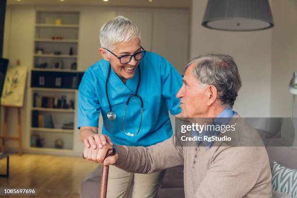 mann mit einem stock, blick auf die krankenschwester - house call stock-fotos und bilder