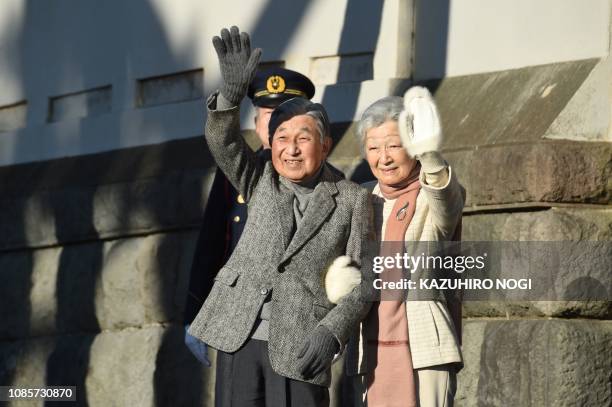 Japan's Emperor Akihito and Empress Michiko wave to well-wishers at the end of their stroll on a beach near the Hayama Imperial Villa in Hayama,...