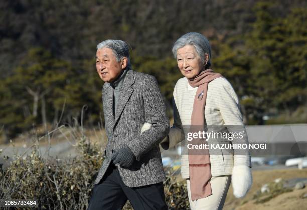 Japan's Emperor Akihito and Empress Michiko stroll on a beach near the Hayama Imperial Villa in Hayama, Kanagawa Prefecture on January 21, 2019....