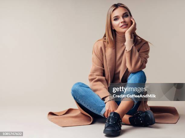 smiling woman sitting on the floor - beige fashion stock pictures, royalty-free photos & images