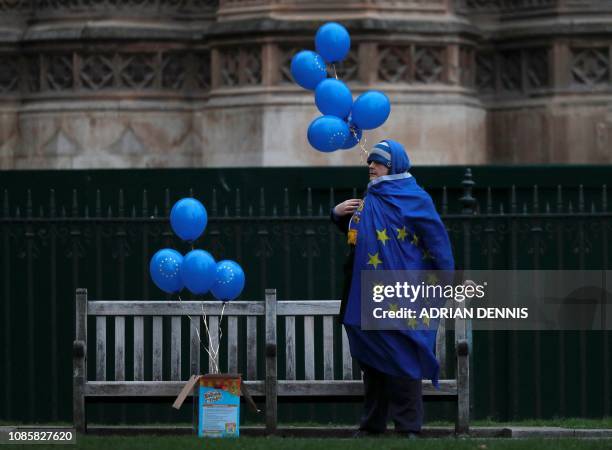 An anti-Brexit activist wrapped in an EU flag holds EU flag-themed balloons as they demonstrate outside of the Houses of Parliament in central London...