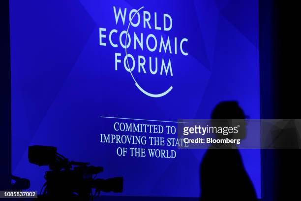 An illuminated display screen silhouettes a worker inside the Congress Center ahead of the World Economic Forum in Davos, Switzerland, on Monday,...