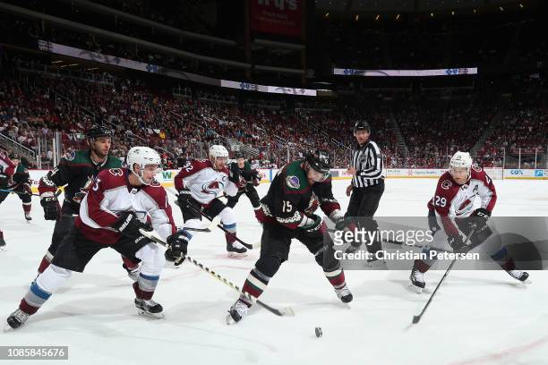 Brad Richardson of the Arizona Coyotes attempts to control the puck in-between Alexander Kerfoot and Nathan MacKinnon of the Colorado Avalanche...