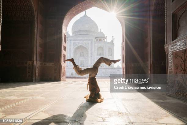 young woman practicing yoga in india at the famous taj mahal at sunrise - headstand position upside down- people travel spirituality zen like concept - yoga retreat stock pictures, royalty-free photos & images