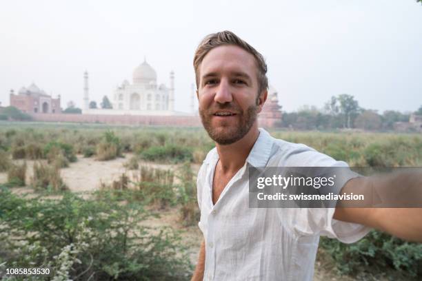 tourist male taking selfie at the famous taj mahal at sunset using mobile phone, agra, india. people travel asia concept - taj mahal selfie stock pictures, royalty-free photos & images