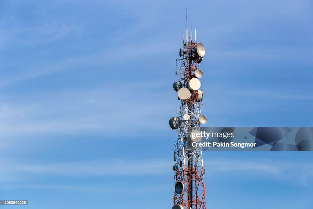 Telecommunication mast with microwave link and TV transmitter antennas over a blue sky.