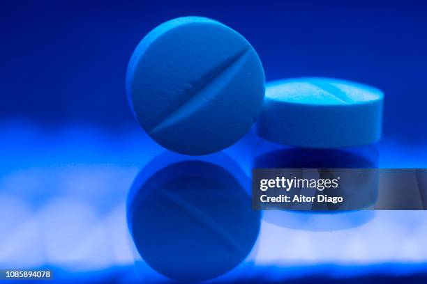 two pills on reflective and illuminated surface. research, laboratory blue tone. conceptual nature - generiskt läkemedel bildbanksfoton och bilder