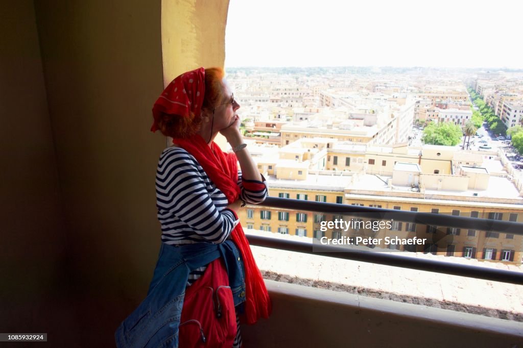 Mujer mirando a la ciudad mientras está parada en el balcón
