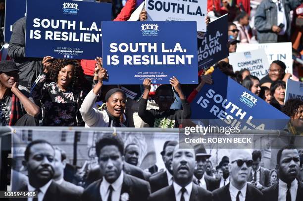 People hold signs as they watch the 34th annual Kingdom Day Parade on Martin Luther King Jr Day, January 21 in Los Angeles, California.