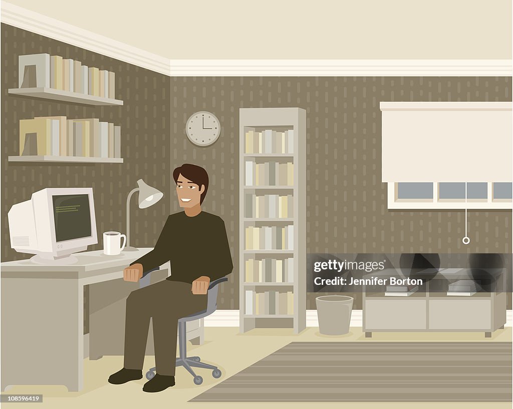 Young Man Sitting at Computer Desk in Home Office