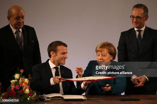 January 2019, North Rhine-Westphalia, Aachen: Emmanuel Macron, President of France, and German Chancellor Angela Merkel , sign the treaty, observed...