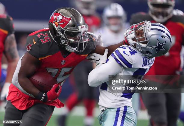 Peyton Barber of the Tampa Bay Buccaneers stiff arms Chidobe Awuzie of the Dallas Cowboys on a carry in the third quarter at AT&T Stadium on December...