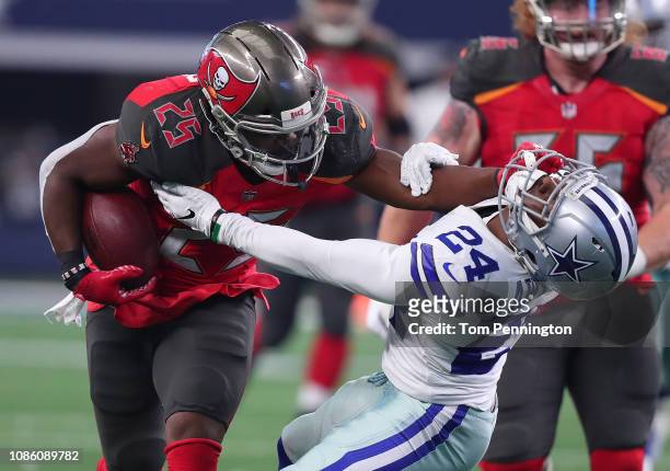 Peyton Barber of the Tampa Bay Buccaneers stiff arms Chidobe Awuzie of the Dallas Cowboys on a carry in the third quarter at AT&T Stadium on December...