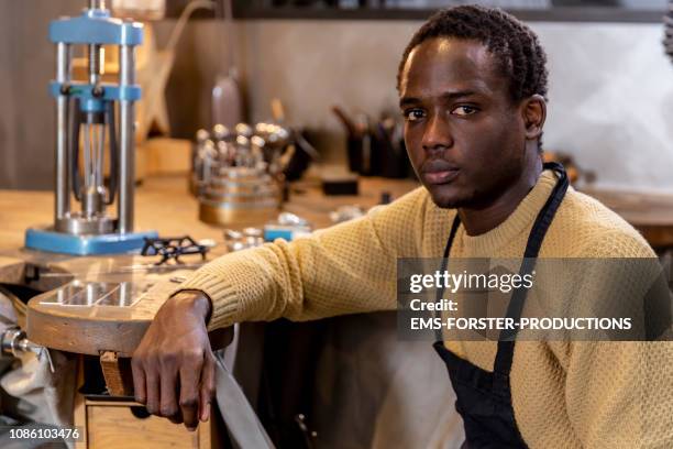 portrait of an african goldsmith in his small jewelry store - migrant worker stock-fotos und bilder