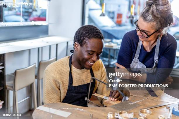 goldsmith workshop and retail shop led by independent master craftswoman with male apprentice of african origin - fugitivo stock-fotos und bilder