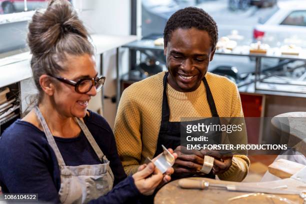 goldsmith workshop and retail shop led by independent master craftswoman with male apprentice of african origin - fugitive stock pictures, royalty-free photos & images