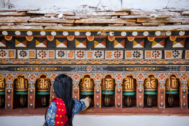 a woman reaching for a prayer bell - bhutan stock pictures, royalty-free photos & images
