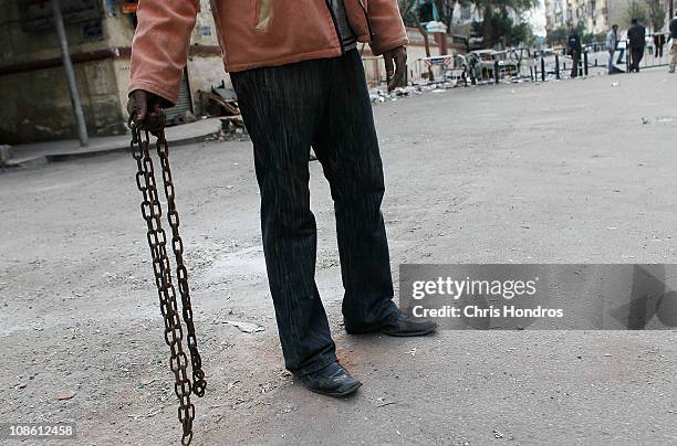 An Egyptian man holds a chain as part of a ad-hoc neighborhood security militia in residential neighborhood in central Cairo the afternoon of January...