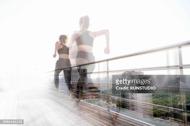 young woman running on rooftop - double exposure running stock-fotos und bilder
