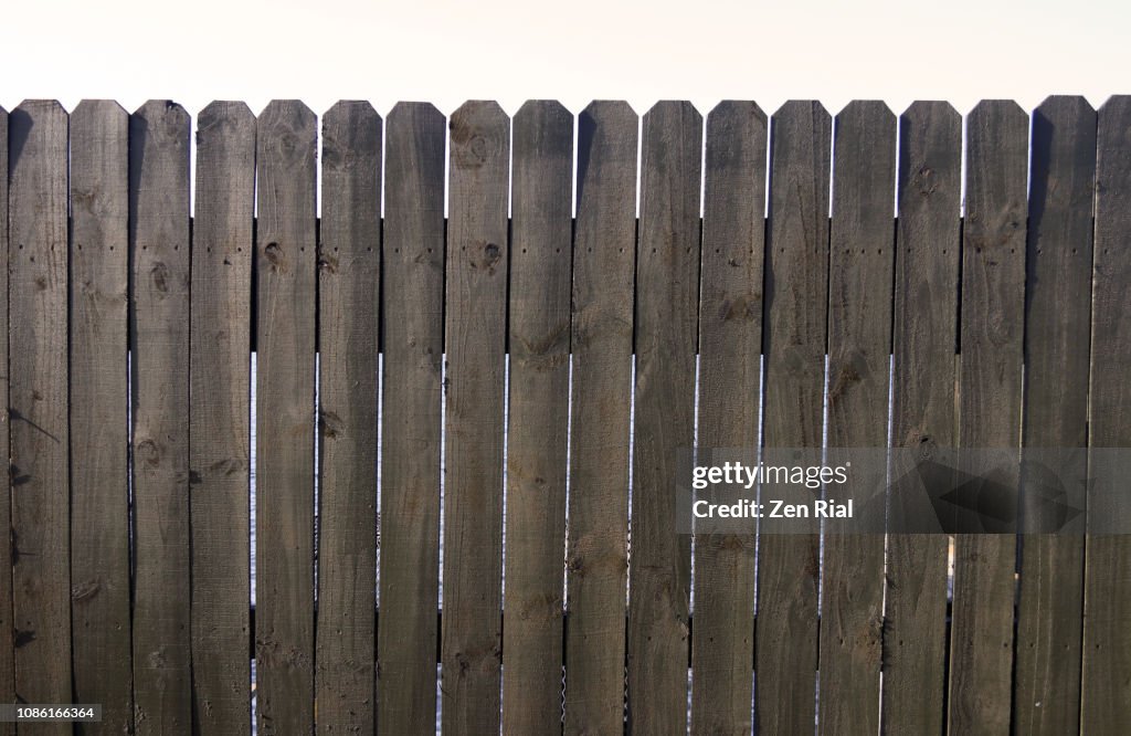 Old unpainted wooden picket fence against white background