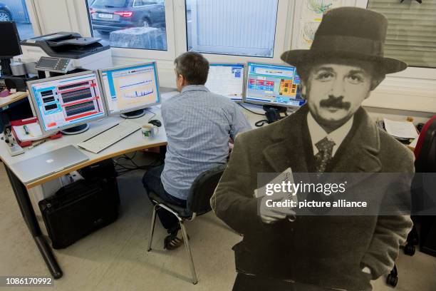 January 2019, Lower Saxony, Sarstedt: An employee sits in front of screens in the GEO600 detector next to a cardboard display by Albert Einstein. The...