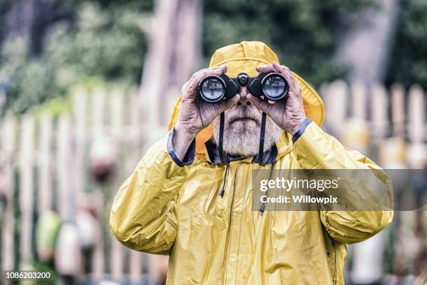 sea captain looking at camera through binoculars - sailor rain stock pictures, royalty-free photos & images