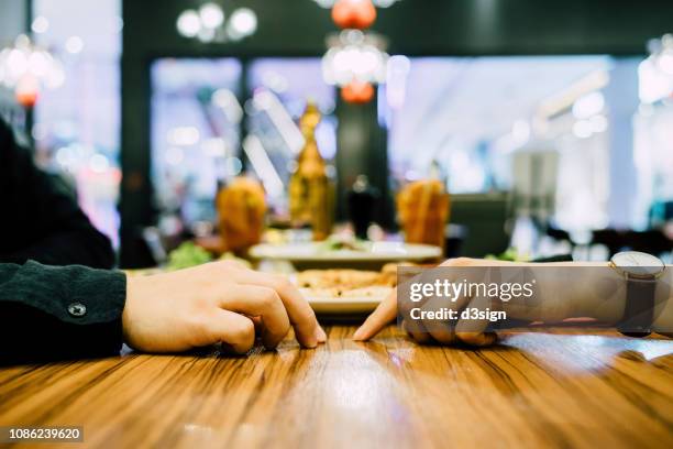 couple going on a first date and attempting to hold hands during a dinner date at a restaurant - uomo donna per mano foto e immagini stock