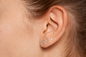 Closeup of female ear with three earrings
