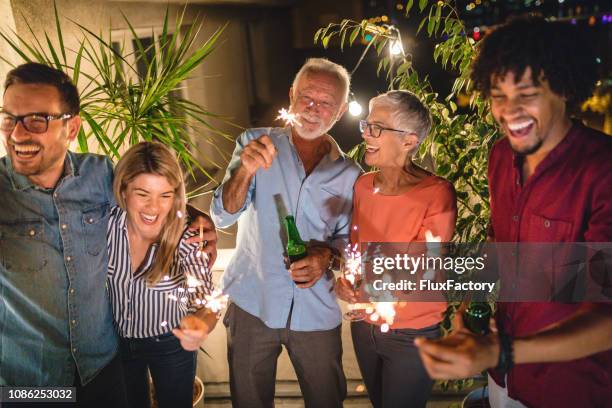 group of close friends celebrating new year on a cityscape rooftop - family new year's eve stock pictures, royalty-free photos & images